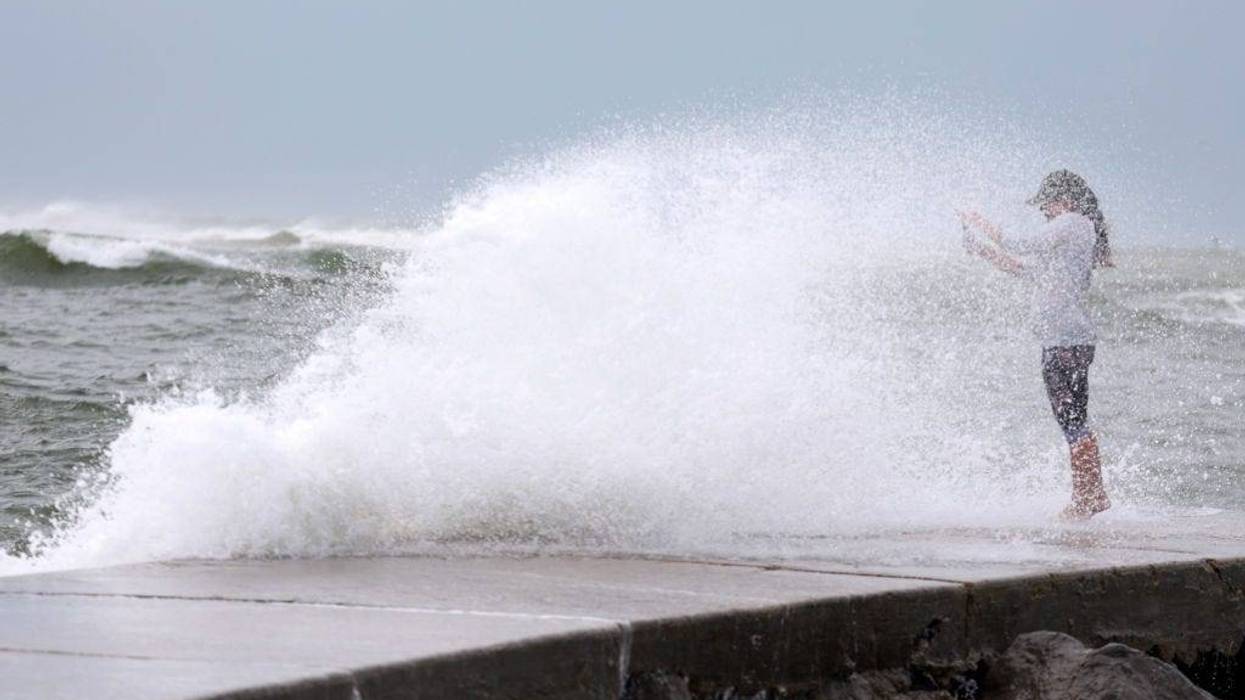 Valerie Barrington gets caught in a wave crashing ashore from the Gulf of Mexico as Hurricane Helene passes offshore on September 26, 2024 in St. Pete Beach, Florida.