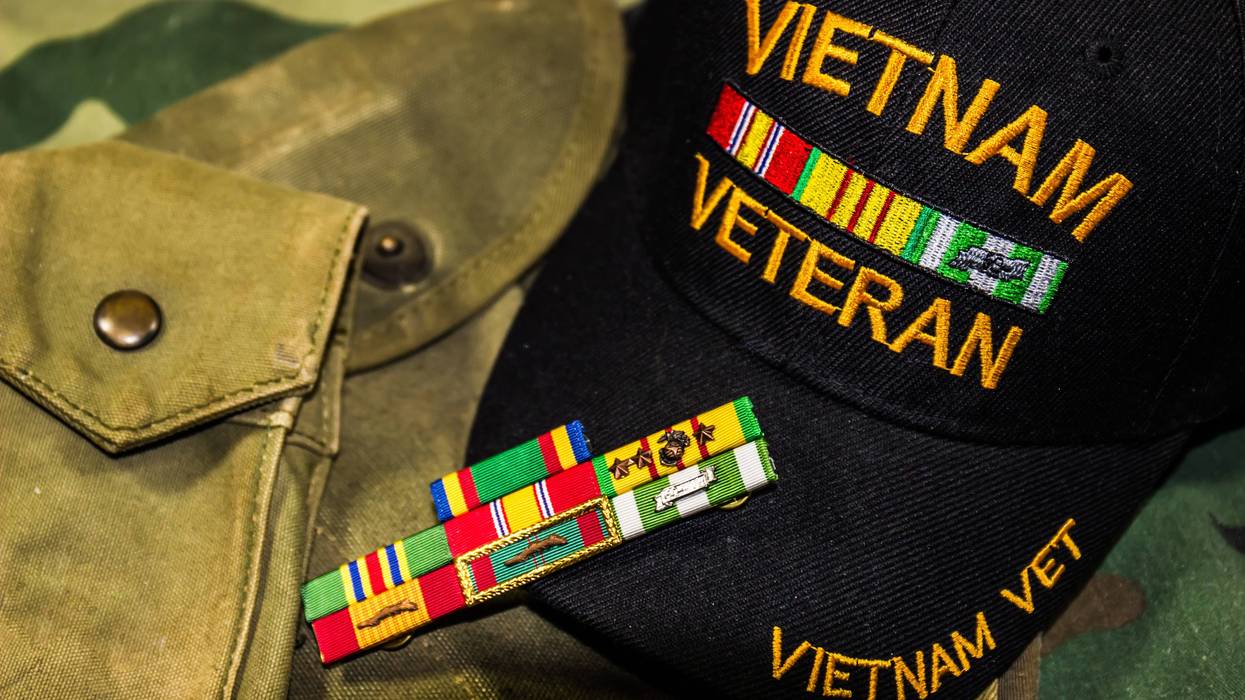 Vietnam Veterans hat, service ribbons and pouches on camouflage uniform