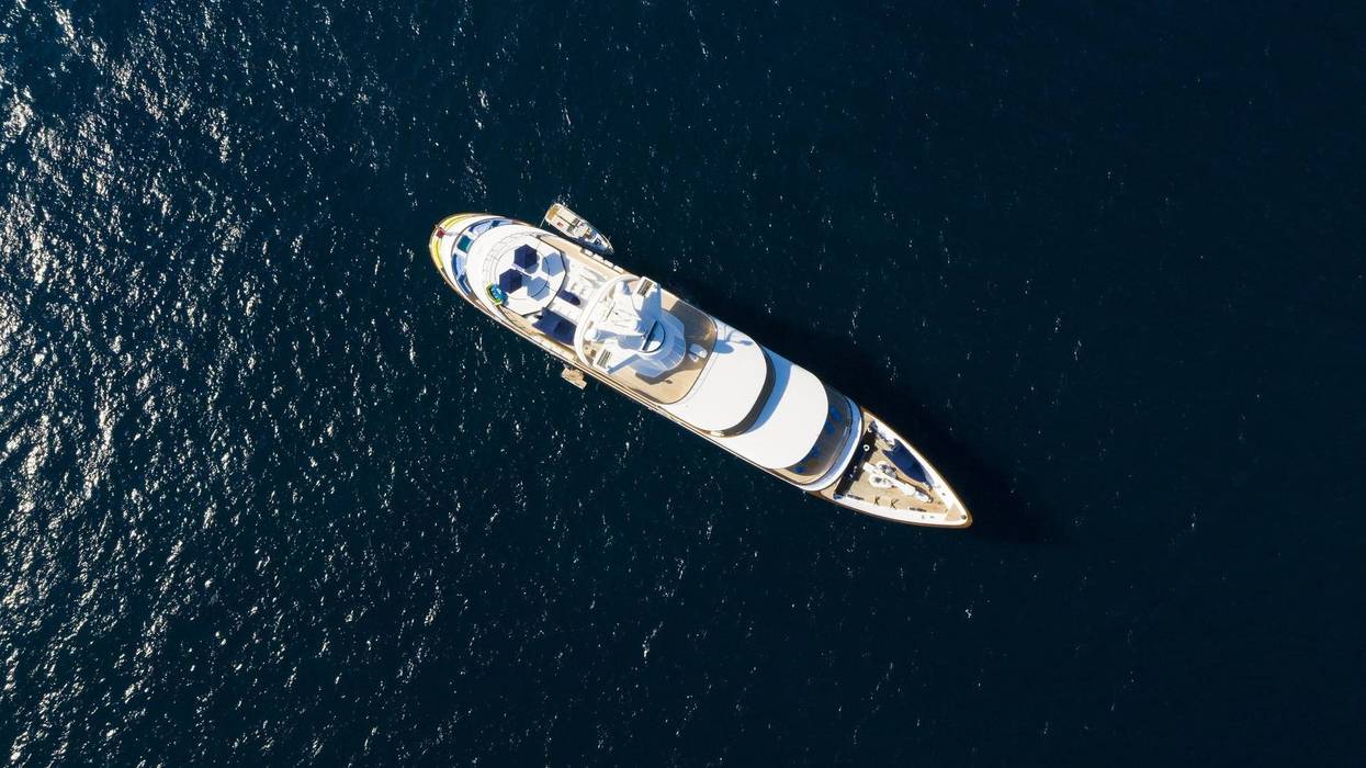 View from above, stunning aerial view of a luxury yacht sailing on a blue sea. Emerald Coast (Costa Smeralda) Sardinia, Italy.