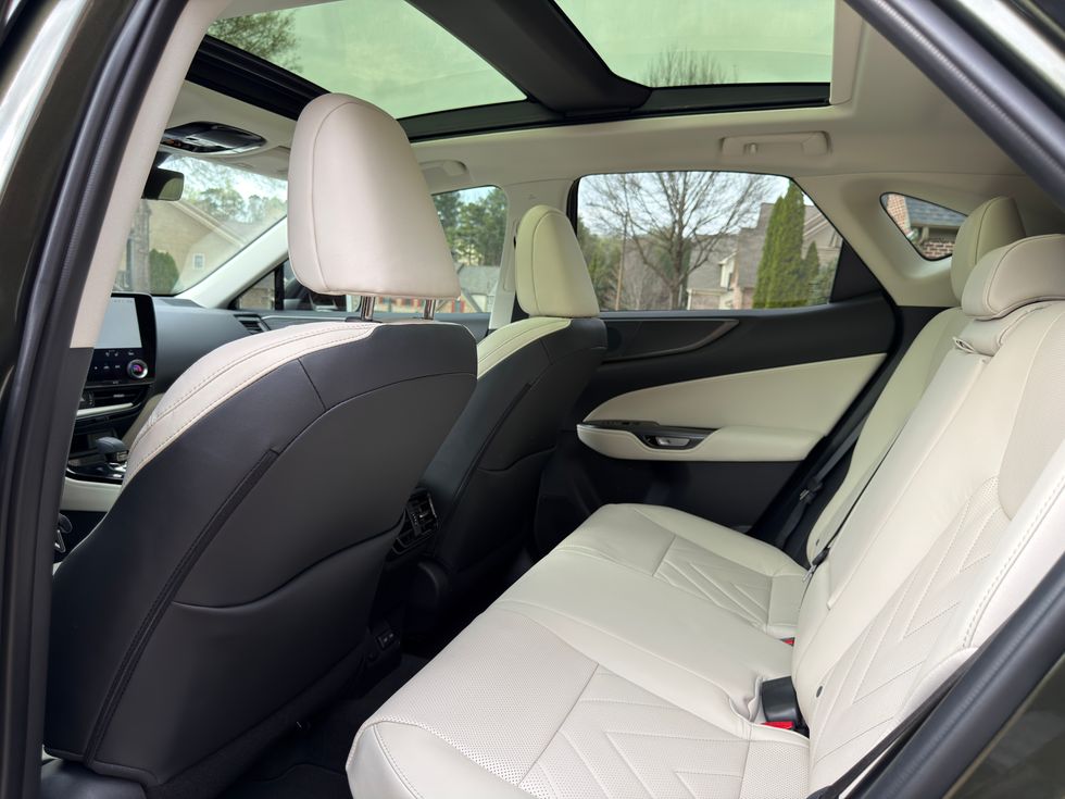 View from car's back seat: two-tone cream and black interior with a panoramic sunroof.