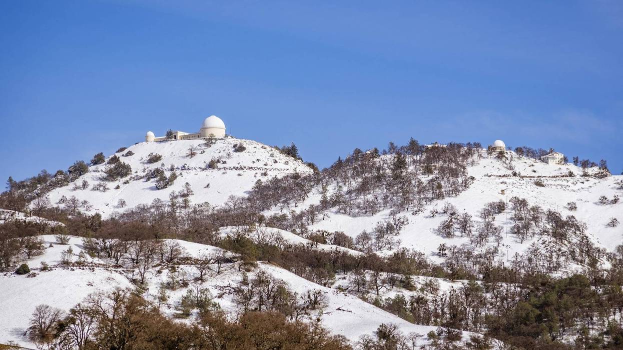 View towards the top of Mt. Hamilton on a clear winter day, with snow covering the summit and the surrounding hills.