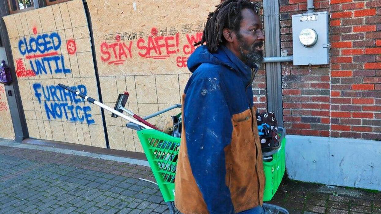 Vincent Amos, who identified himself as homeless, pulls a shopping cart with his belongings amid businesses closed by concerns of the COVID-19 coronavirus in the Deep Ellum section of Dallas.
