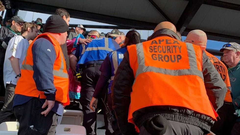 Vincent Basile (in sunglasses and Mummers costume) talking with first responders after helping an unconscious man during the Eagles-Saints game Sunday at Lincoln Financial Field.