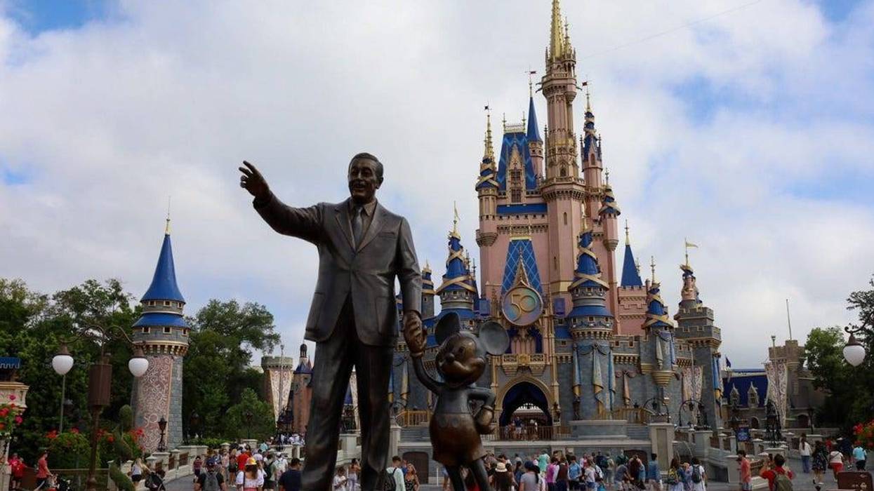 visitors to Disney's Magic Kingdom pass a statue of Walt Disney holding hands with Mickey Mouse