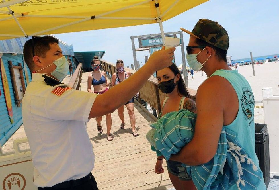 Visitors wear face masks and undergo mandatory temperature checks before entering the pier on Independence Day on July 4th in Cocoa Beach, Florida
