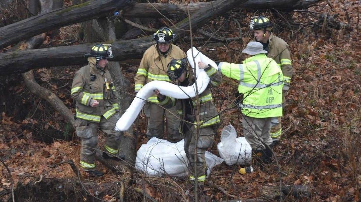 Volunteer firefighters work to clean up an oil spill in Central Perkiomen Valley Park Friday.