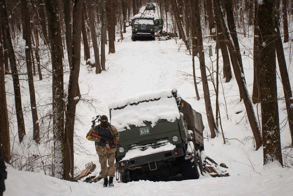 Volunteers of the Ukrainian Territorial Defense Forces inspect a damaged military vehicle in the outskirts of Kharkiv, Ukraine