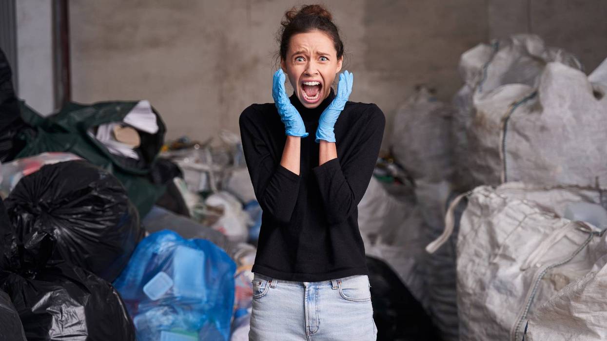 Waist up portrait of shocked caucasian woman screaming with hands near her face while working at the waste recycling plant