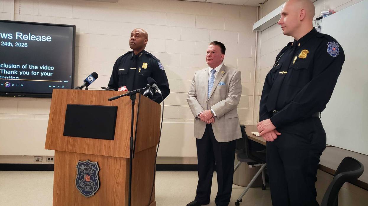 Warren Police Chief at podium with microphones, joined by a man in suit and an officer.