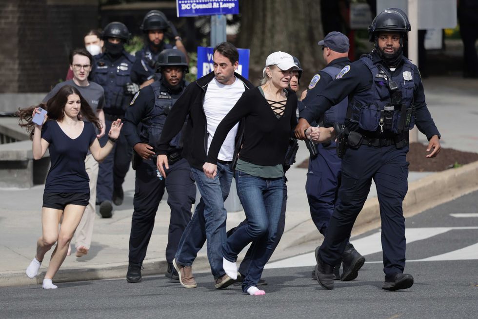 WASHINGTON, DC - APRIL 22: Metropolitan Police run as they escort people, some without shoes, away from a shooting scene in the northwest part of the city on April 22, 2022 in Washington, DC. Police evacuated residents from the shooting scene Friday afternoon and there were reports of several shooting victims.