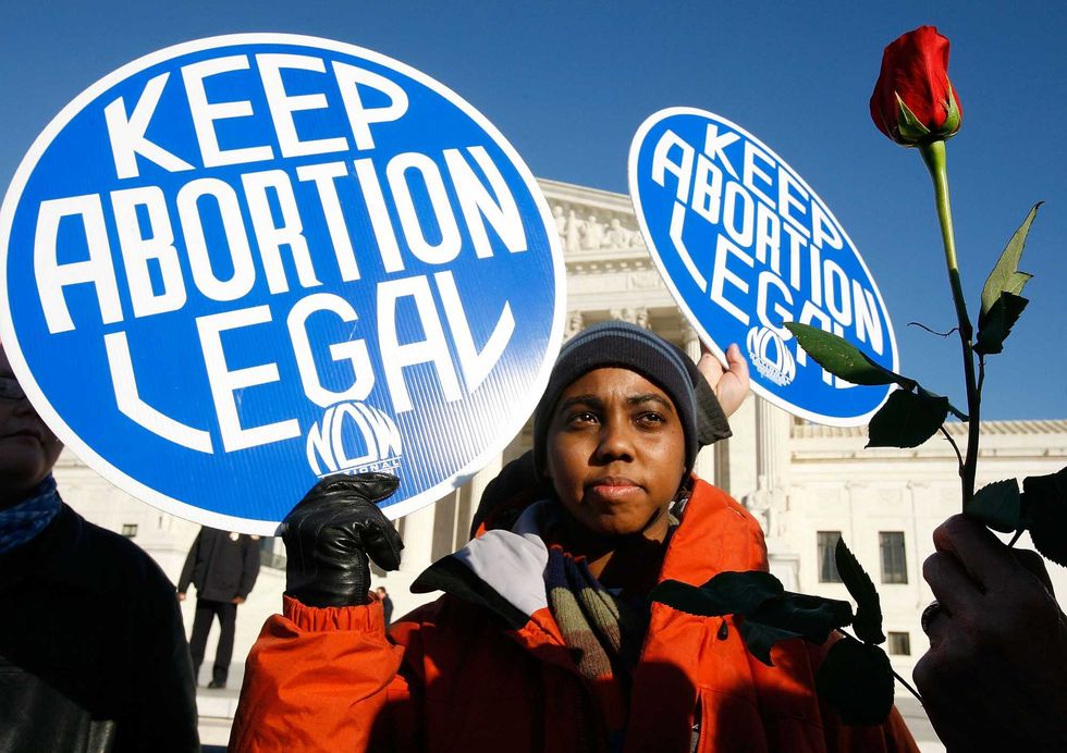 WASHINGTON - JANUARY 22: Local pro-choice activist Lisa King holds a sign in front of the U.S. Supreme Court as a pro-life activist holds a rose nearby during the annual "March for Life" event January 22, 2009 in Washington, DC. The event was to mark the anniversary of the 1973 Roe v Wade Supreme Court abortion ruling. (Photo by Alex Wong/Getty Images)