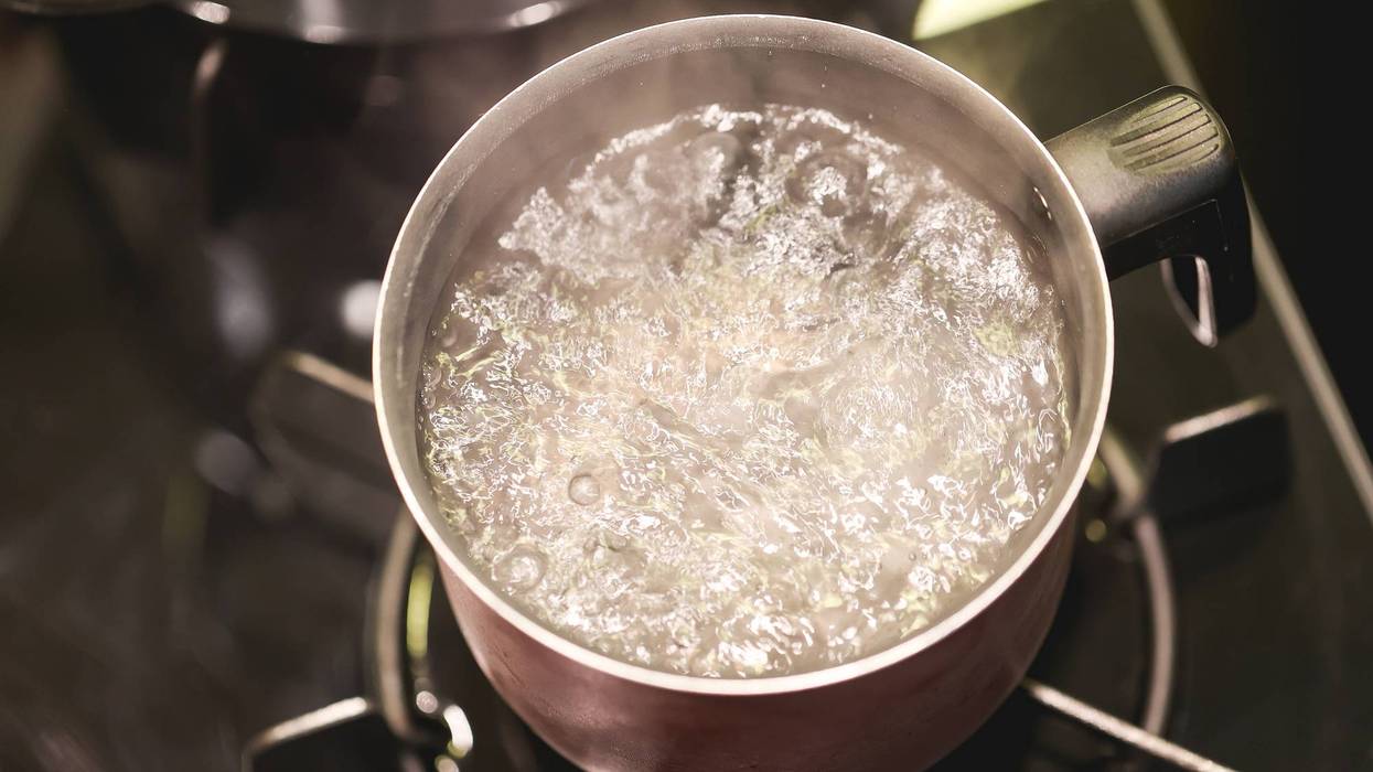 Water boiling in a kettle over a dark stove.