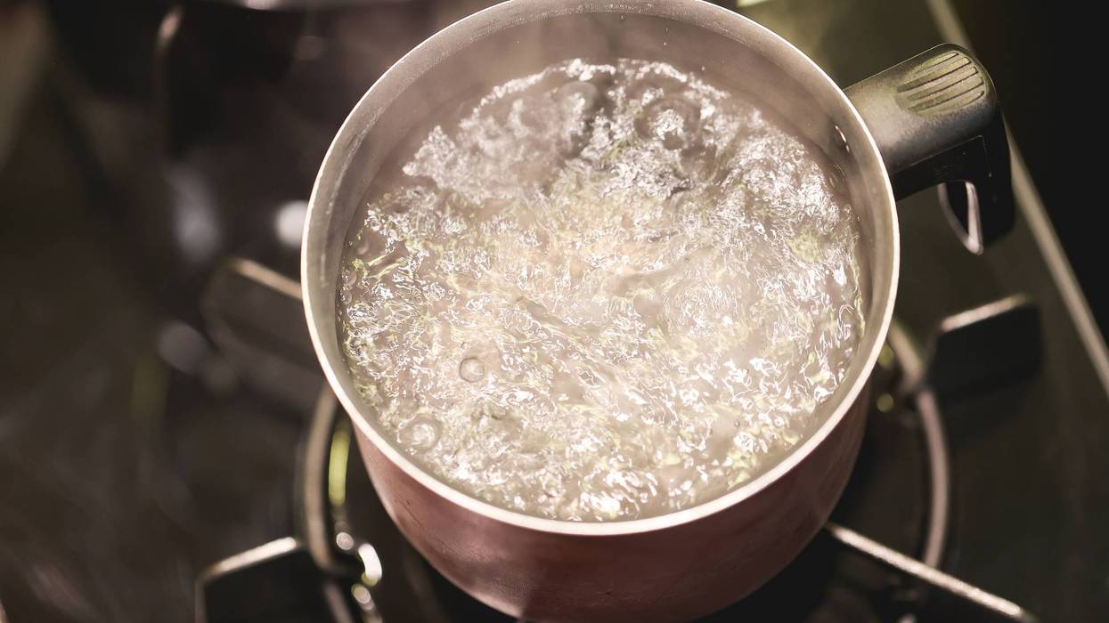 Water boiling in a kettle over a dark stove.
