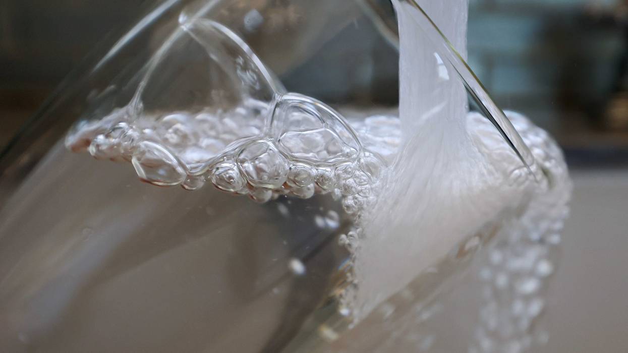 Water pours from a faucet into a glass.