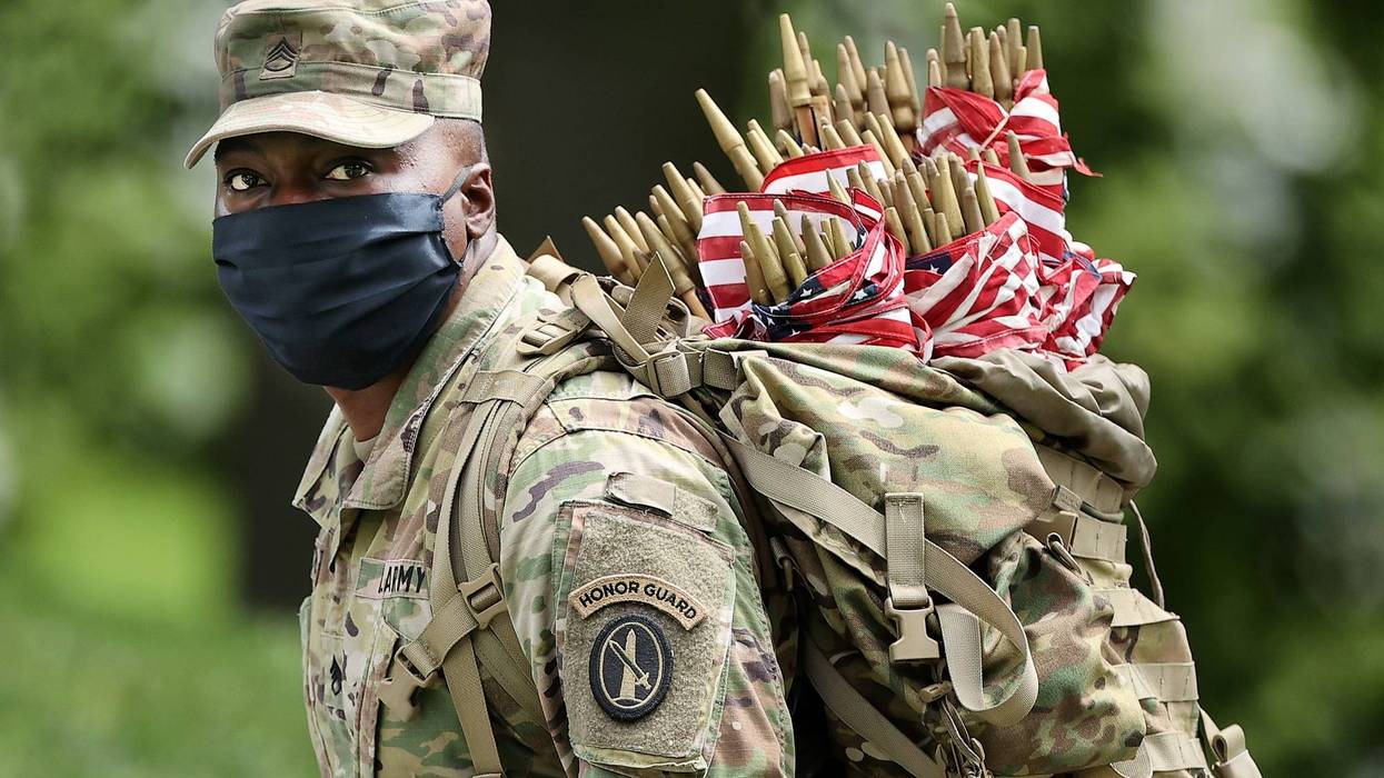 Wearing face masks to reduce the risk of spreading the novel coronavirus, a soldier from the 3rd Infantry Regiment, or the "Old Guard," works to place U.S. flags in front of every grave site ahead of the Memorial Day weekend in Arlington National Cemetery on May 21, 2020 in Arlington, Virginia. Traditionally known as "Flags-In," soldiers place small flags in front of more than 228,000 headstones and at the bottom of about 7,000 niche rows in the cemetery's Columbarium Courts and Niche Wall . (Photo by Chip Somodevilla/Getty Images)