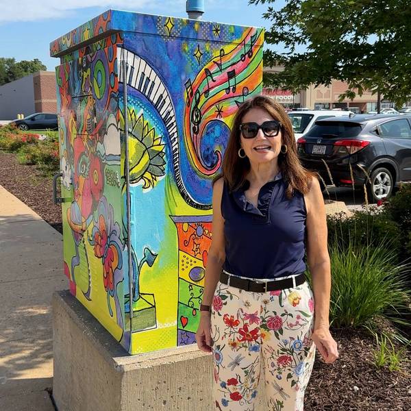 Webster Groves Arts Commission Chair Janice Seele stands with a painted utility box (designed by Genevieve Esson) in Maplewood along Manchester Avenue