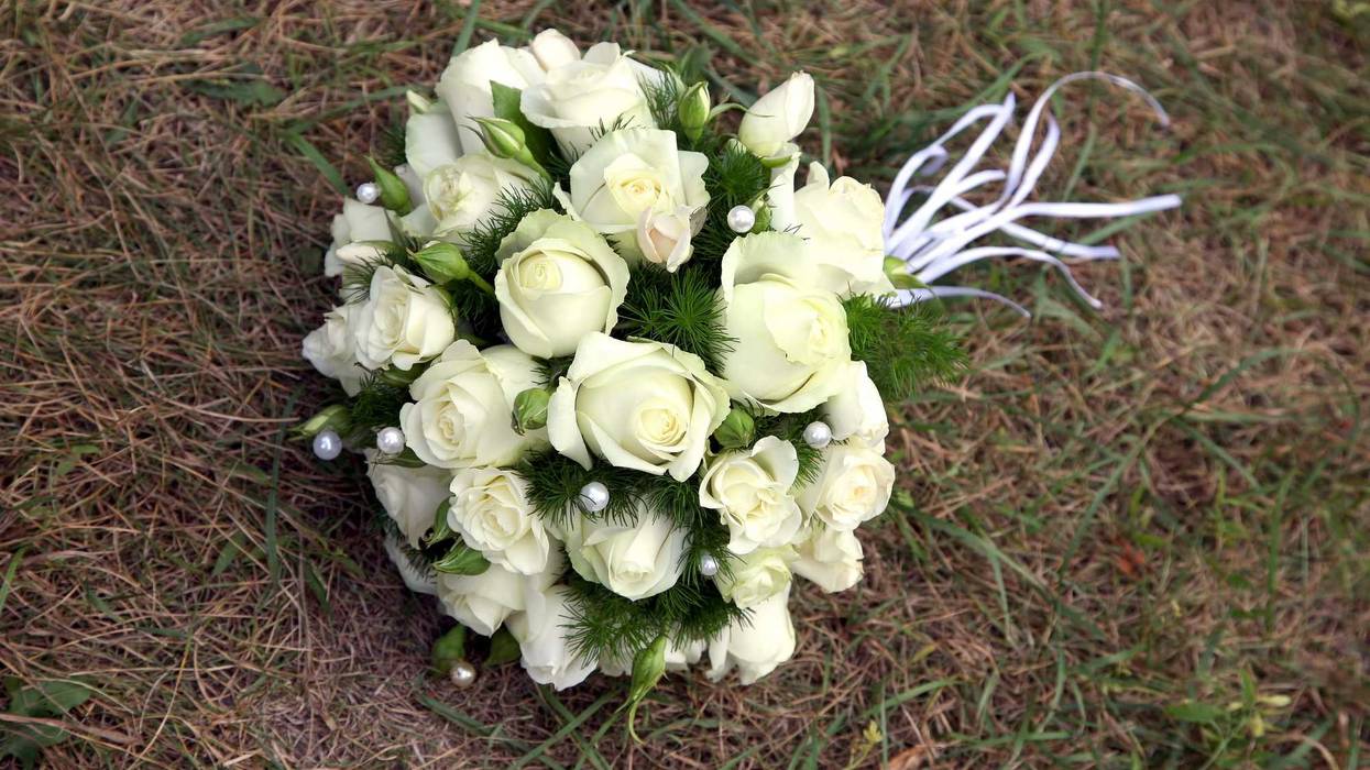 Wedding bouquet of white roses lying on the grass.