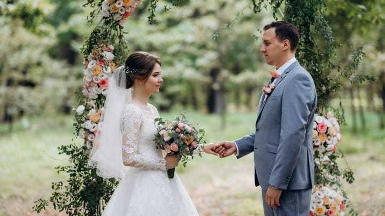 wedding ceremony of the marriage of a guy and a girl against the backdrop of an arch on a forest path