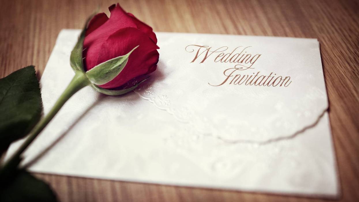 Wedding invitation and red rose on a wooden table