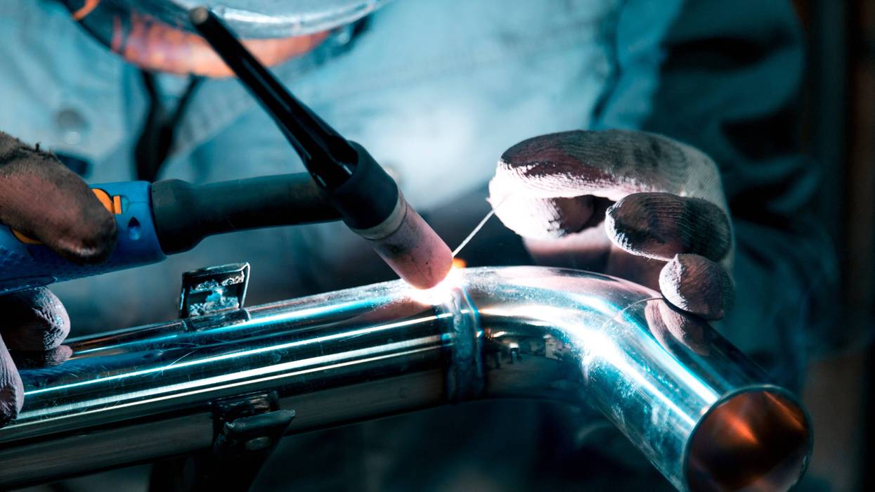 Welder welds a steel pipe