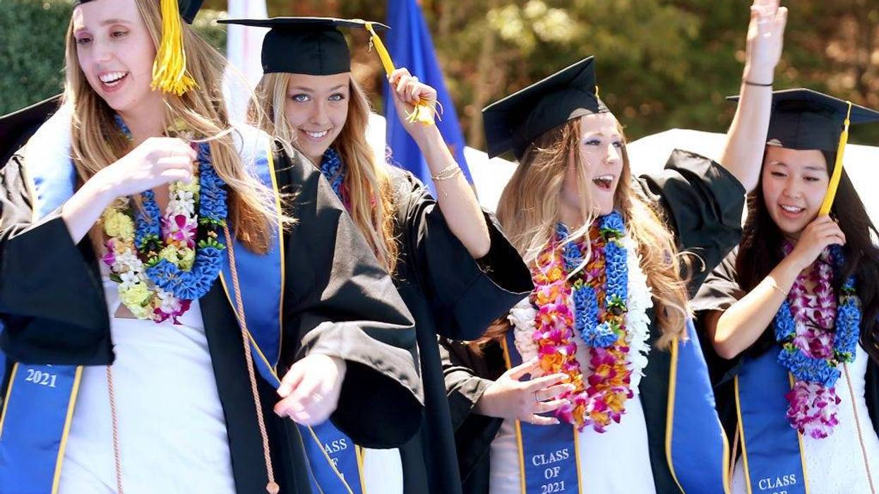 WESTWOOD, CALIFORNIA - JUNE 11: Graduating UCLA students celebrate while walking the stage for their commencement ceremony at Drake Stadium on June 11, 2021 in Westwood, California. Up to 230 students per hour were able to participate in the graduate procession. Each graduate was allowed two guests and were permitted to remove their masks before crossing the stage.