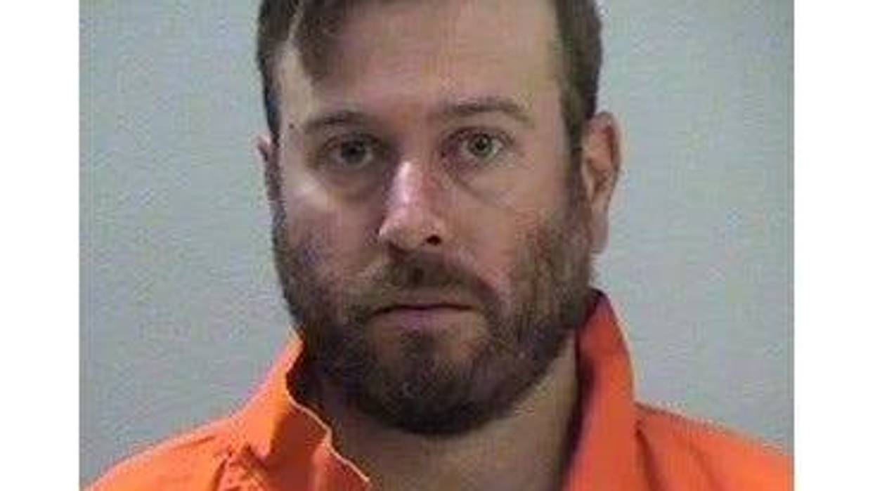 White bearded man in 30's mugshot wearing orange collard button down