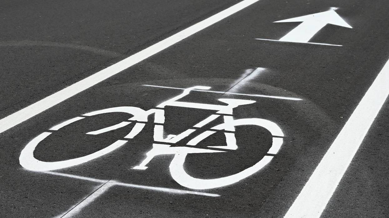 White bicycle symbol and arrow painted on dark asphalt bike lane.