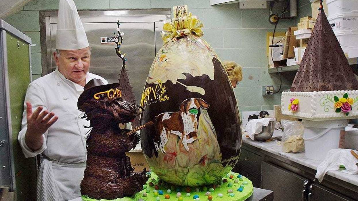 White House Pastry Chef Roland Mesnier present his creation, a 40-pound semi-sweet chocolate Easter Egg decorated with the First Family's pet dogs Barney (L) and Spot in the White House kitchen March 29, 2002 in Washington, DC.