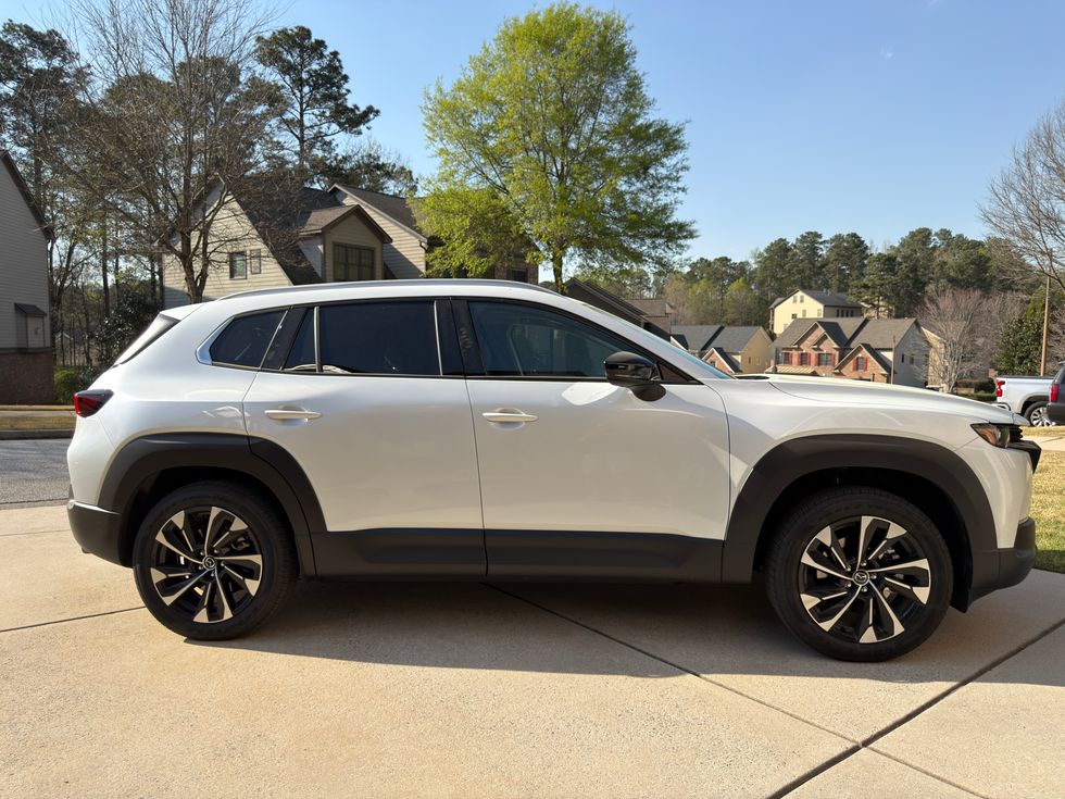 White Mazda CX-50 SUV parked on a driveway in a suburban neighborhood.