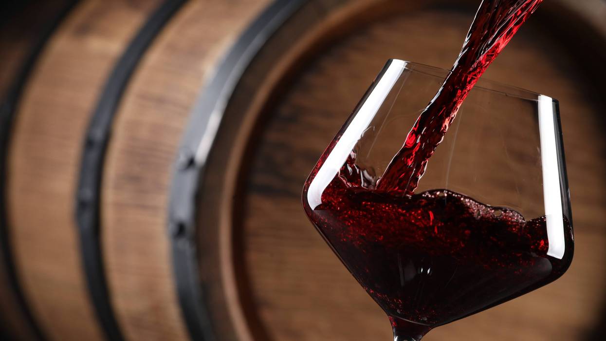 Wine being poured into a glass in front of a barrel