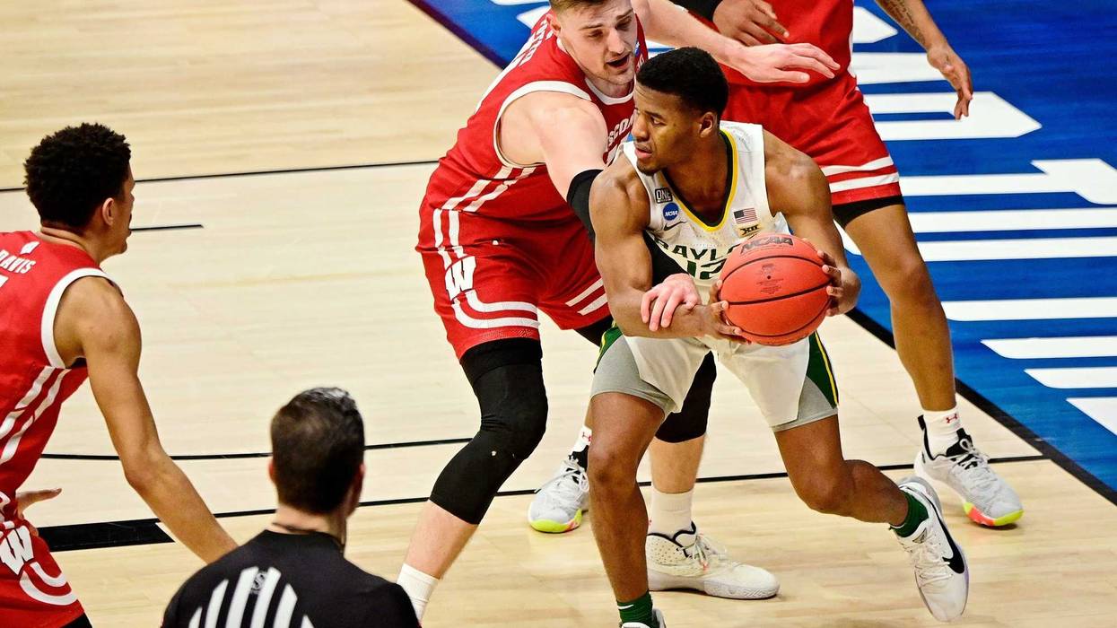 Wisconsin Badgers forward Micah Potter (11) reaches for the ball while defending Baylor Bears guard Jared Butler (12) during the second half in the second round of the 2021 NCAA Tournament at Hinkle Fieldhouse. The Baylor Bears won 76-63.