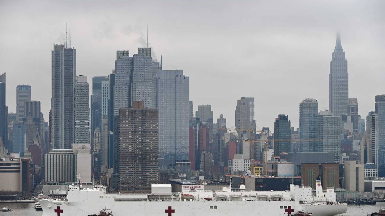 With the Manhattan skyline in the background, the USNS Comfort sails into New York Harbor and up the Hudson River on March 30, 2020