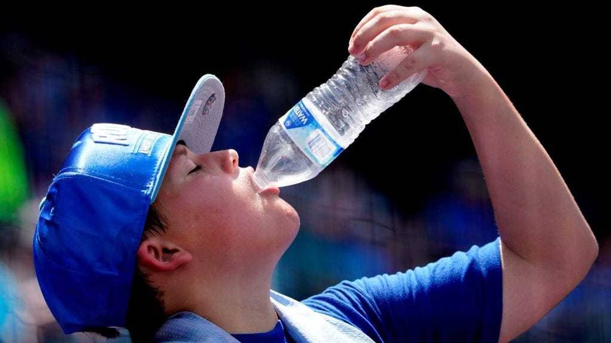 With the temperature nearing 100 degrees, a fans cools himself down by drinking water during a game between the Chicago White Sox and Kansas City Royals at Kauffman Stadium on July 29, 2021 in Kansas City, Missouri.