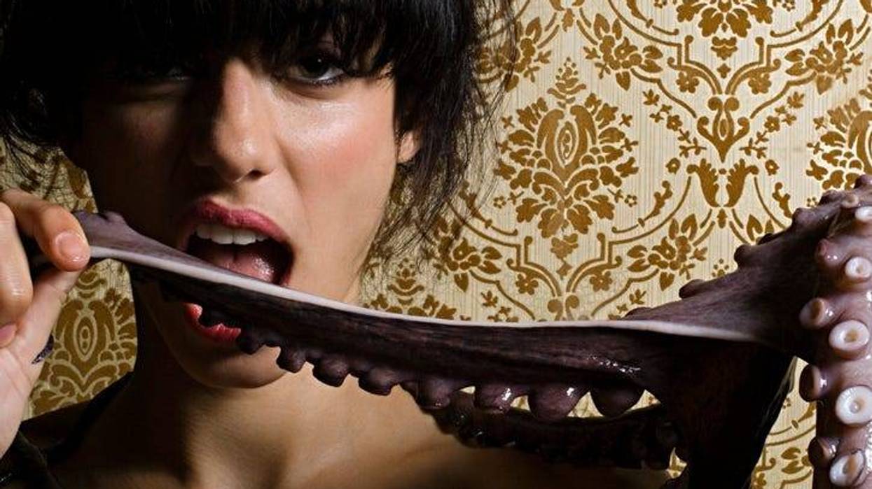 Woman biting an octopus tentacle