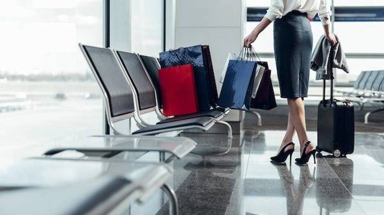 Woman carrying shopping bags and luggage while in airport