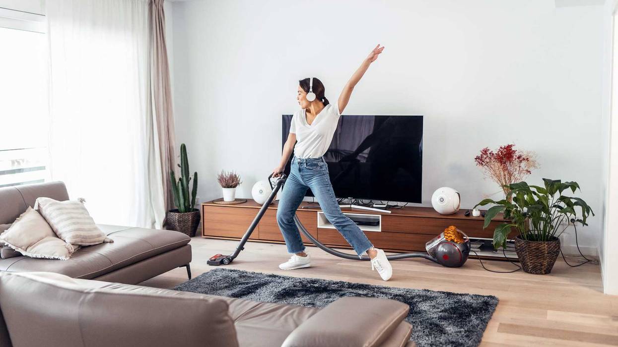 Woman cleaning with a vacuum. Happy.