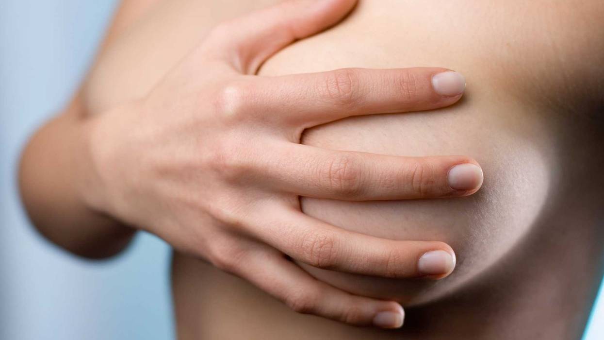 Woman covering her breasts with her hand.