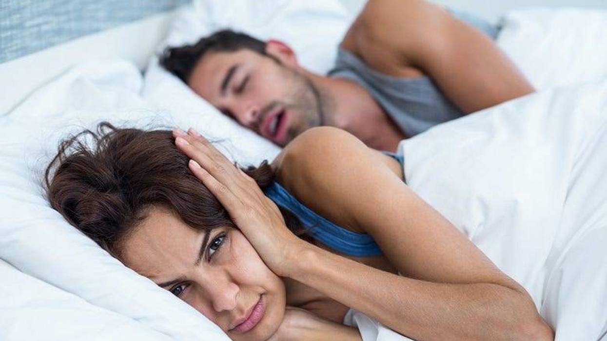 woman covering her ears because of man's snoring