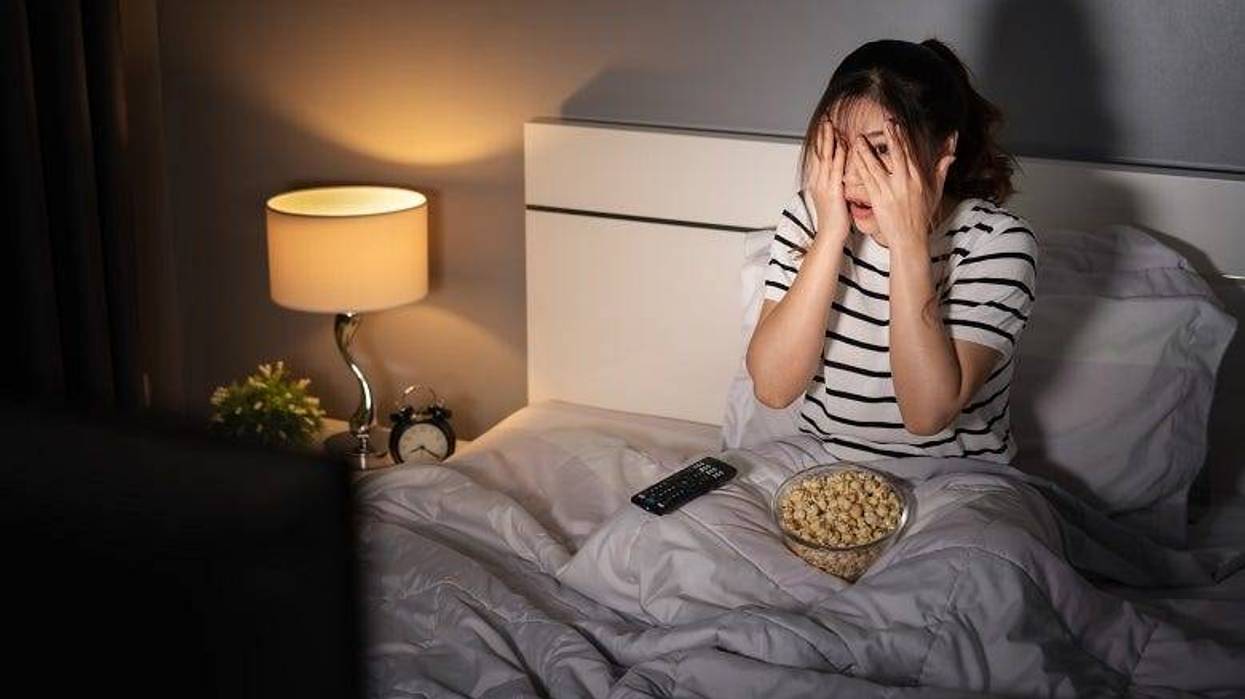 woman covering her eyes while watching TV