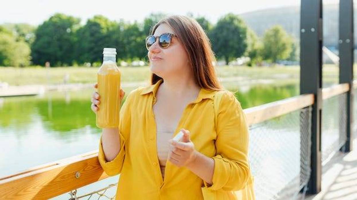 Woman drinking a bottle of orange juice outdoors