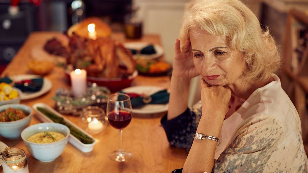 Woman feeling lonely and missing her family at dining table on Thanksgiving.