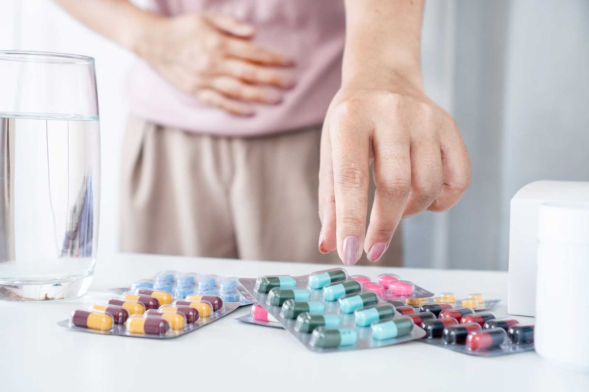 Woman grabbing for pills on a table.