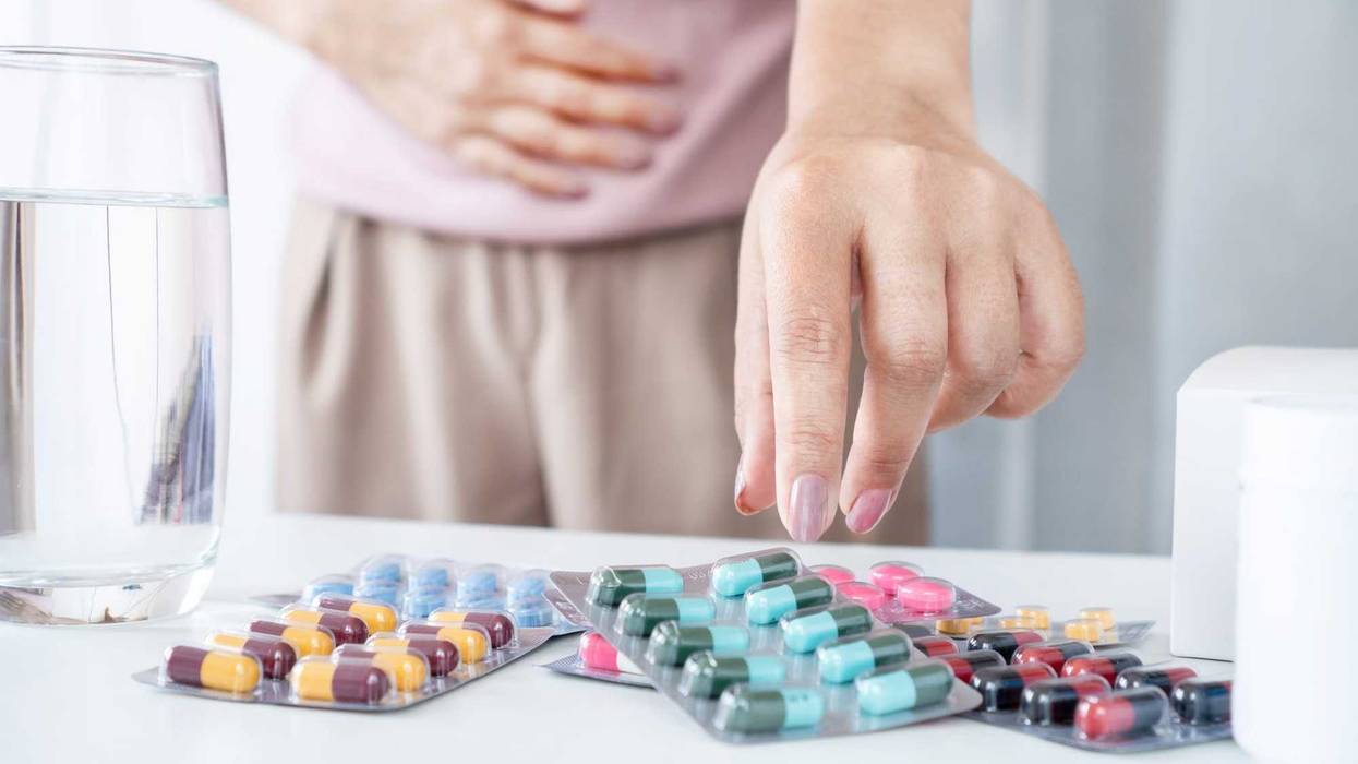 Woman grabbing for pills on a table.