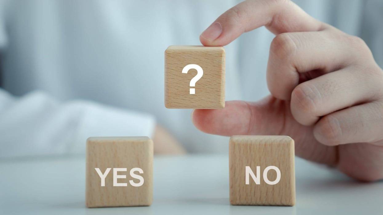 Woman hand holding question mark on wooden blocks with YES and NO word - stock photo