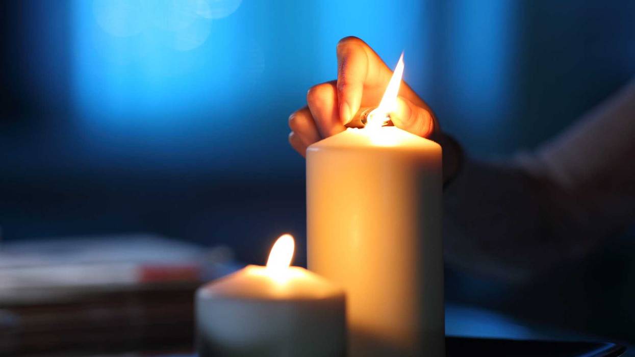 Woman hand lighting candle in the night at home