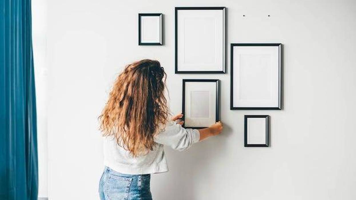 Woman hanging a frame on a wall