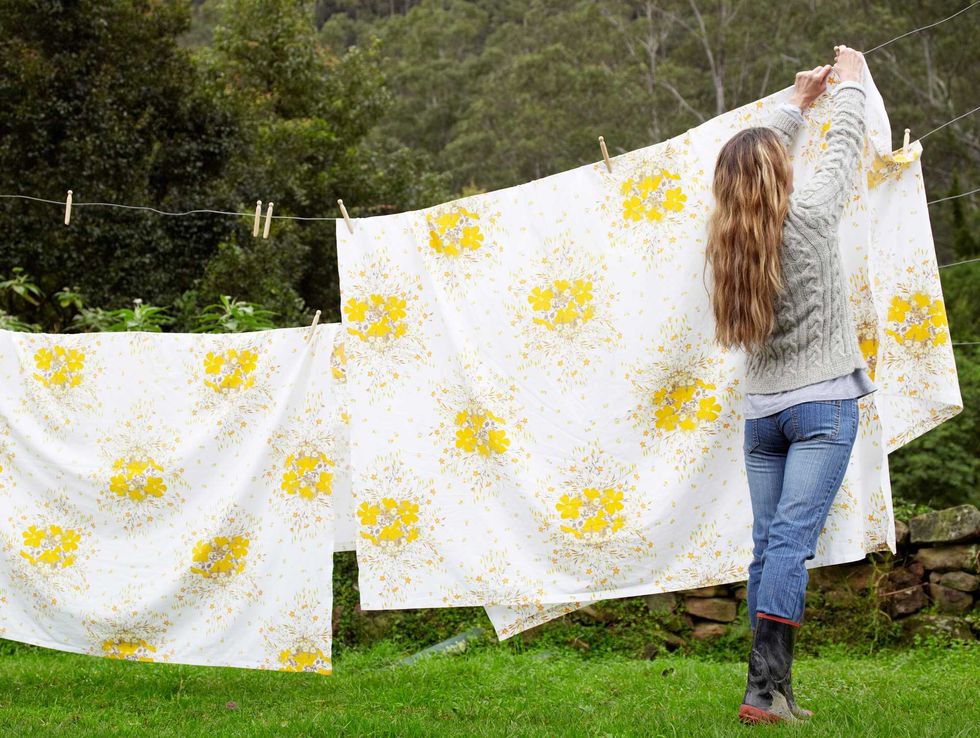 Woman hanging sheets on a clothesline.