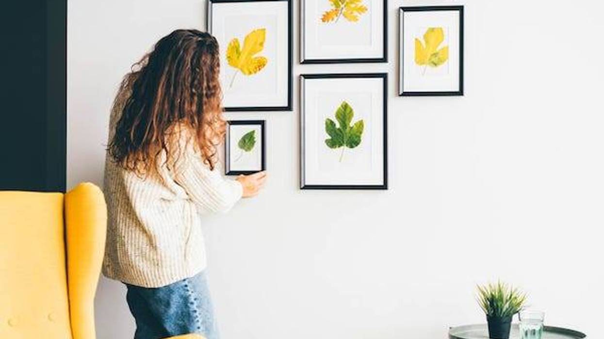 Woman hanging up art on wall