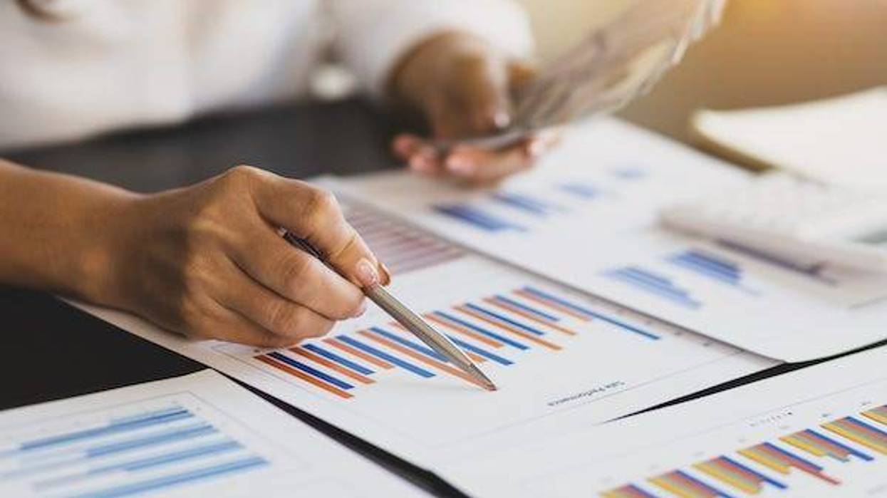 Woman holding cash and looking at accounting report