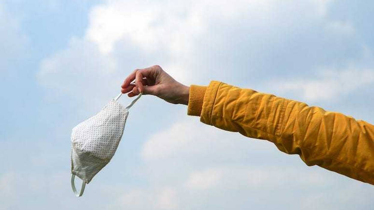 Woman holding face mask, Blue Sky